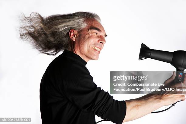 mature man using hair dryer and smiling, side view - tousled hair man stock pictures, royalty-free photos & images