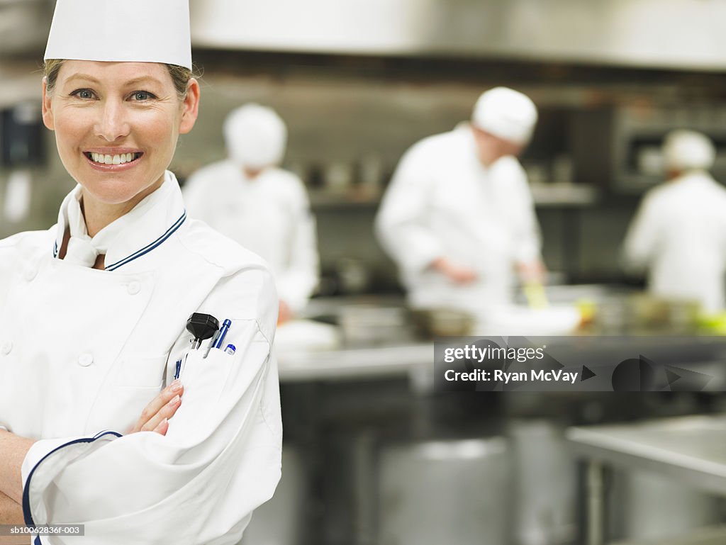 Chef in commercial kitchen, portrait, others in background