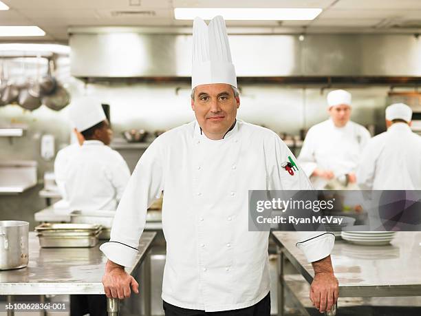 chef standing in front of others working in commercial kitchen, portrait - uniforme de chef fotografías e imágenes de stock