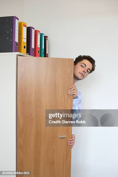 businessman peering from behind office filing cabinet - regarder à la dérobée photos et images de collection