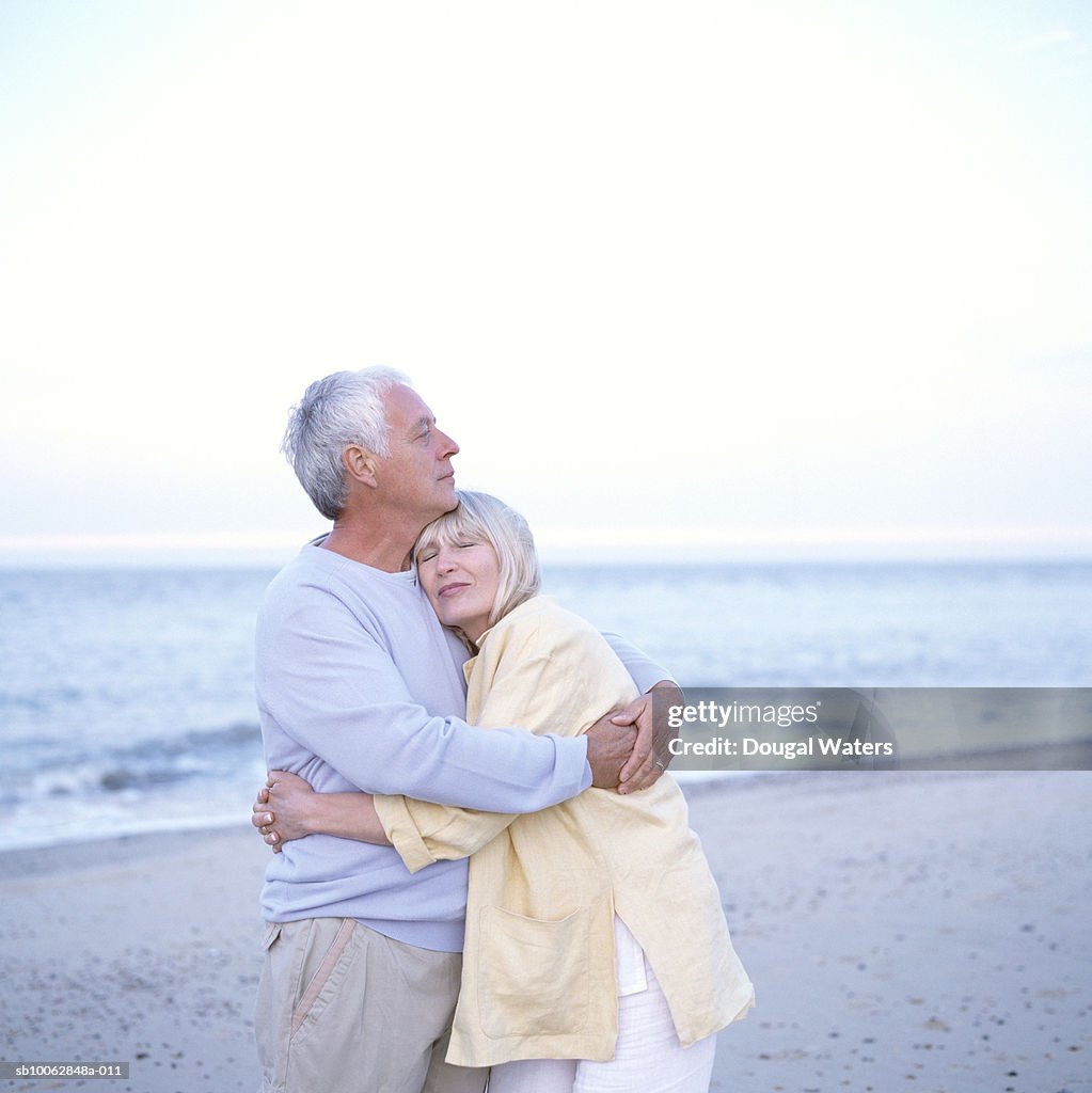 Mature couple standing on beach embracing