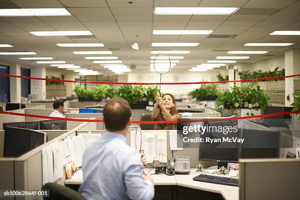 two office workers play badminton across cubicles - badminton sport stockfoto's en -beelden