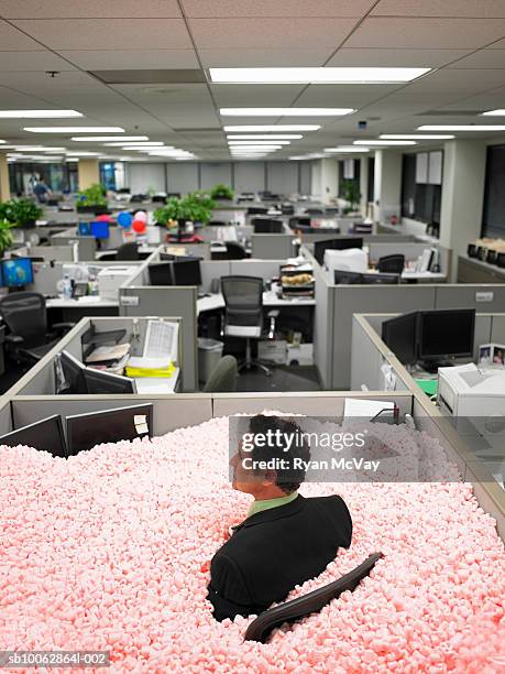 male office worker engulfed in cubicle full of shipping peanuts - mischief stock pictures, royalty-free photos & images