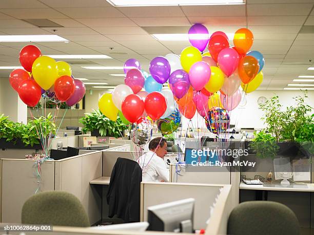 man working in cubicle surround by balloons - balloon knot stock pictures, royalty-free photos & images