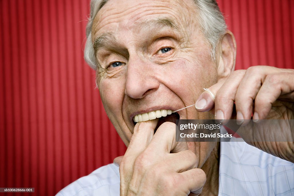 Senior man using dental floss to clean teeth, close-up