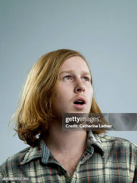 close-up of young man wearing flannel shirt, looking up with open mouth, studio shot - plaid shirt stock pictures, royalty-free photos & images