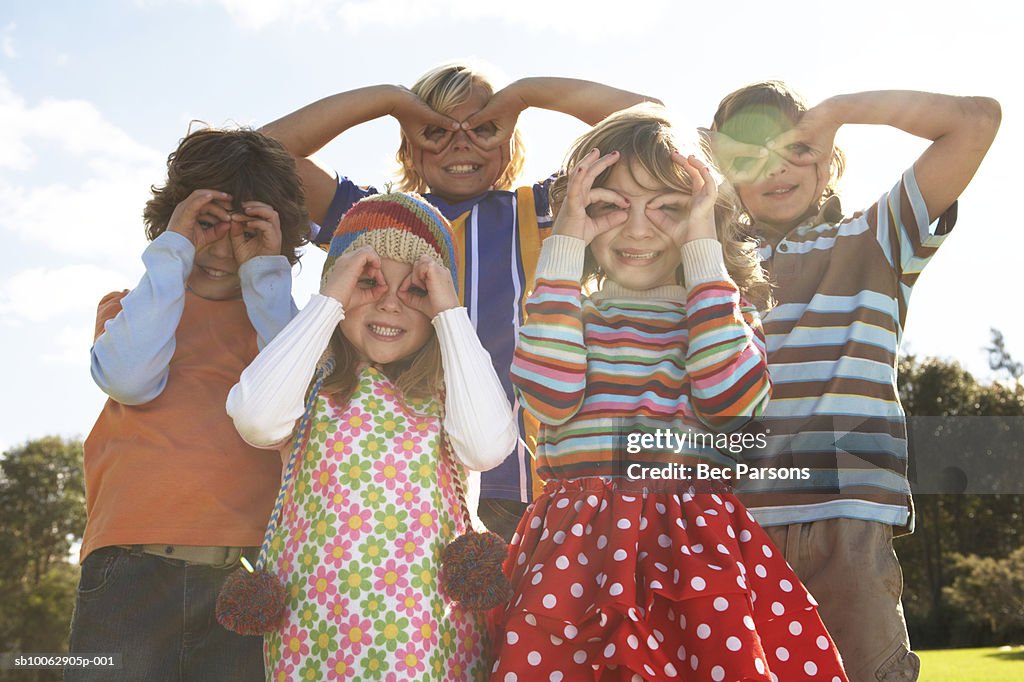 Five children (7-12) with fingers over eyes, portrait (lens flare)