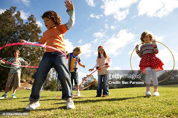 five children (7-12) playing with plastic hoops in park - playing stock pictures, royalty-free photos & images