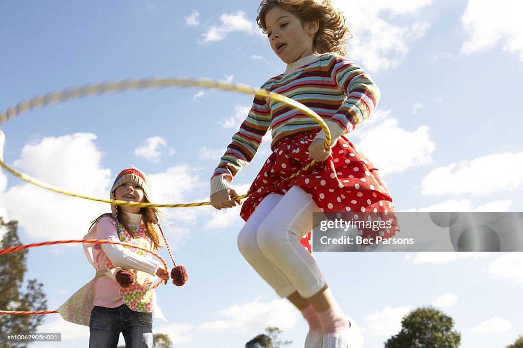 Two girls (7-9) playing with plastic hoops in park (blurred motion)