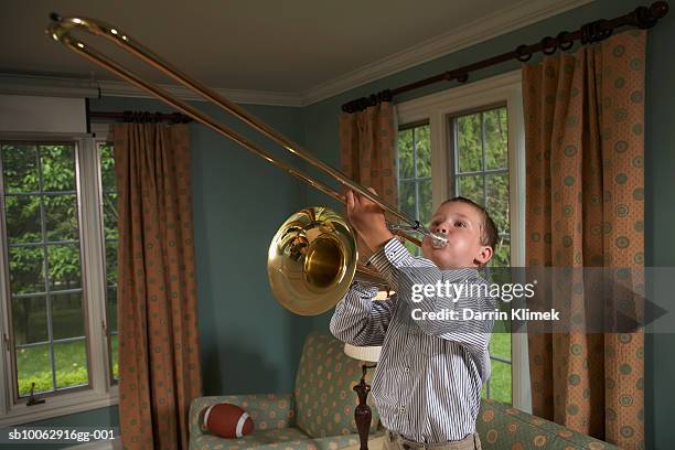 young boy (6-7 years) playing trombone in living room - trombone stock pictures, royalty-free photos & images