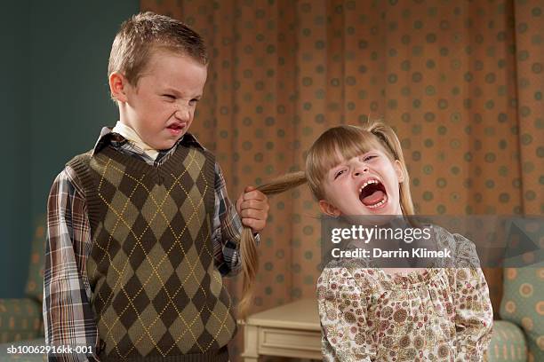 boy (6-7) pulling girl's (4-5) hair in room - demanding stock pictures, royalty-free photos & images