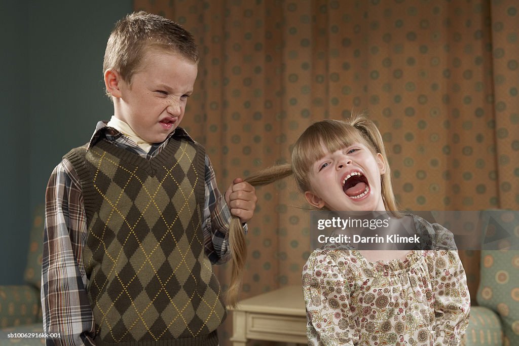 Boy (6-7) pulling girl's (4-5) hair in room
