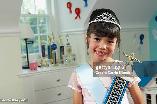 portrait of young girl (8-9 years) indoors, wearing sash and tiara, holding prize, smiling - day 8 bildbanksfoton och bilder