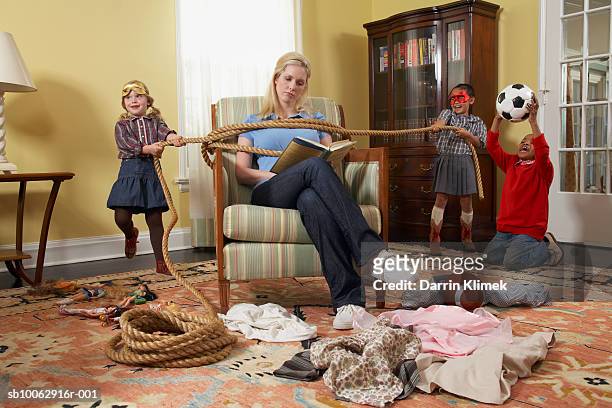 three children (5-7 years) tying mother with rope in living room - vastgebonden stockfoto's en -beelden
