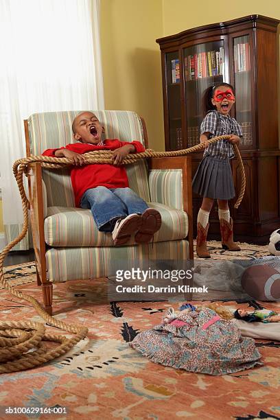 young boy and girl (6-7 years) playing in messy living room, girl tying boy with rope - 6 7 years screaming girl stock-fotos und bilder