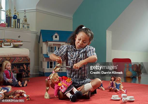 girl (6-7 years) in room, cutting doll's hair - chinese dolls stock pictures, royalty-free photos & images