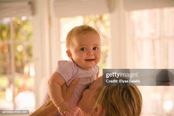 mother holding up baby girl (6-9 months), kissing belly - belly kissing stock pictures, royalty-free photos & images