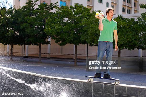 man riding skateboard, carrying tray with coffee, side view - platter side bildbanksfoton och bilder