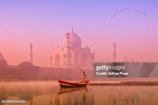 india, uttar pradesh, agra, yamuna river with boatman at dawn, taj mahal in background - agra stock-fotos und bilder