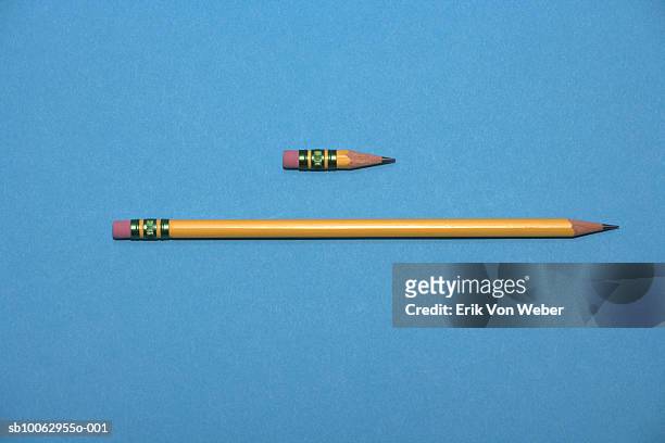 two pencils, new and short one, against blue background - largo longitud fotografías e imágenes de stock