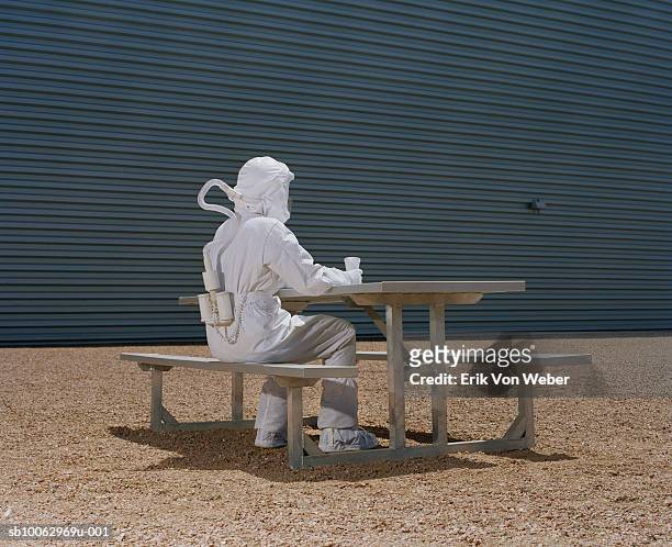 man in protective suit sitting at picnic table - hazmat fotografías e imágenes de stock
