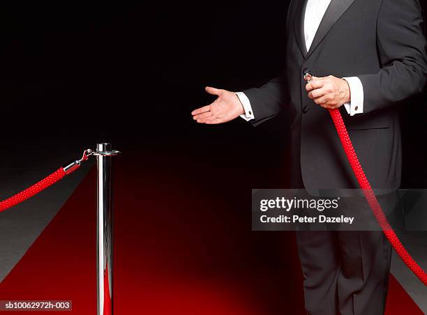 security man showing way past rope on to red carpet, mid section - roped off imagens e fotografias de stock