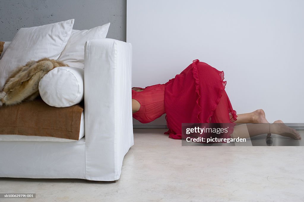 Woman crawling behind sofa, low section, side view