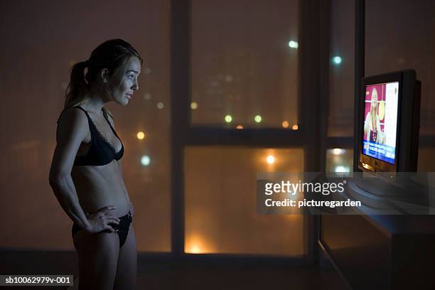 woman in underwear watching tv at night, side view - late night television bildbanksfoton och bilder