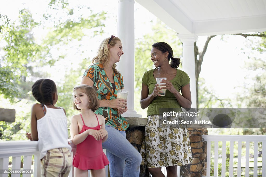 Two women and girls (7-8 years) talking on porch