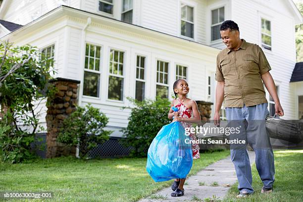 father and daughter (8-9 years) carrying garbage bag in front of house - 8 9 years imagens e fotografias de stock