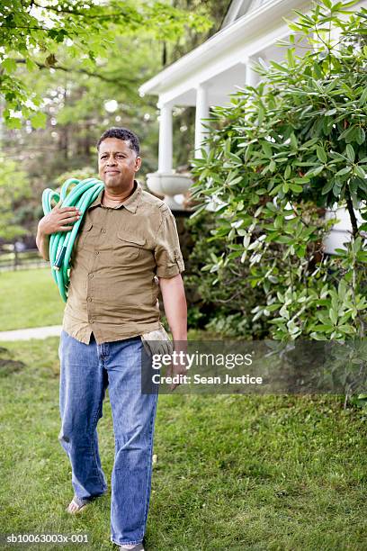 mature man carrying garden hose - sean gardner fotografías e imágenes de stock