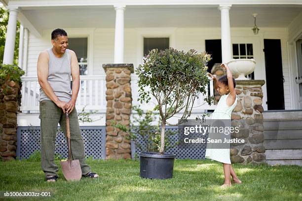 father and daughter (8-9 years) preparing to plant tree in front of house - sean gardner fotografías e imágenes de stock