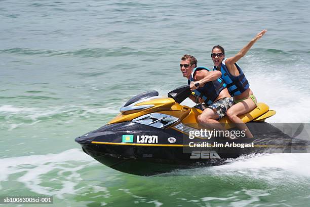 young couple riding jet boat - jet boat fotografías e imágenes de stock