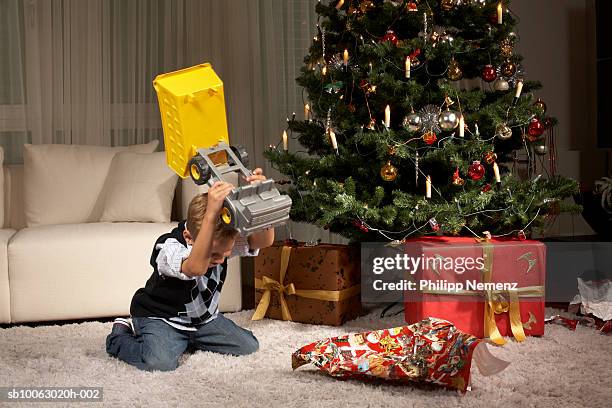 boy (6-7) hitting toy on wrapping paper - christmas stress stock pictures, royalty-free photos & images