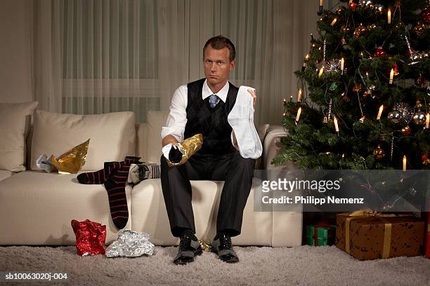 man sitting on sofa holding sock, portrait - delusione foto e immagini stock