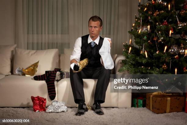 man sitting on sofa holding sock, portrait - christmas present stock pictures, royalty-free photos & images