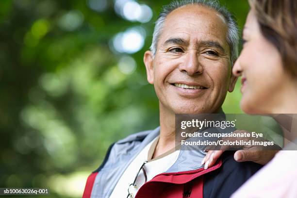 senior couple sitting outdoors, looking in eyes and smiling, close-up (differential focus) - compassionate eye foundation stock-fotos und bilder