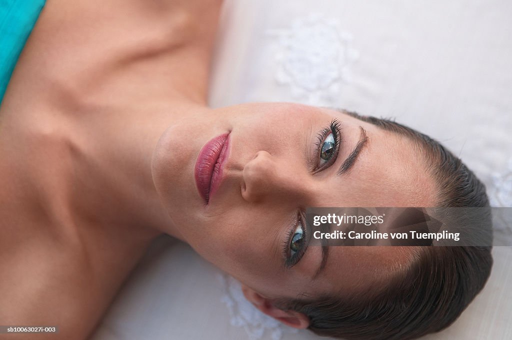 Young woman on massage table, overhead view, portrait, close-up