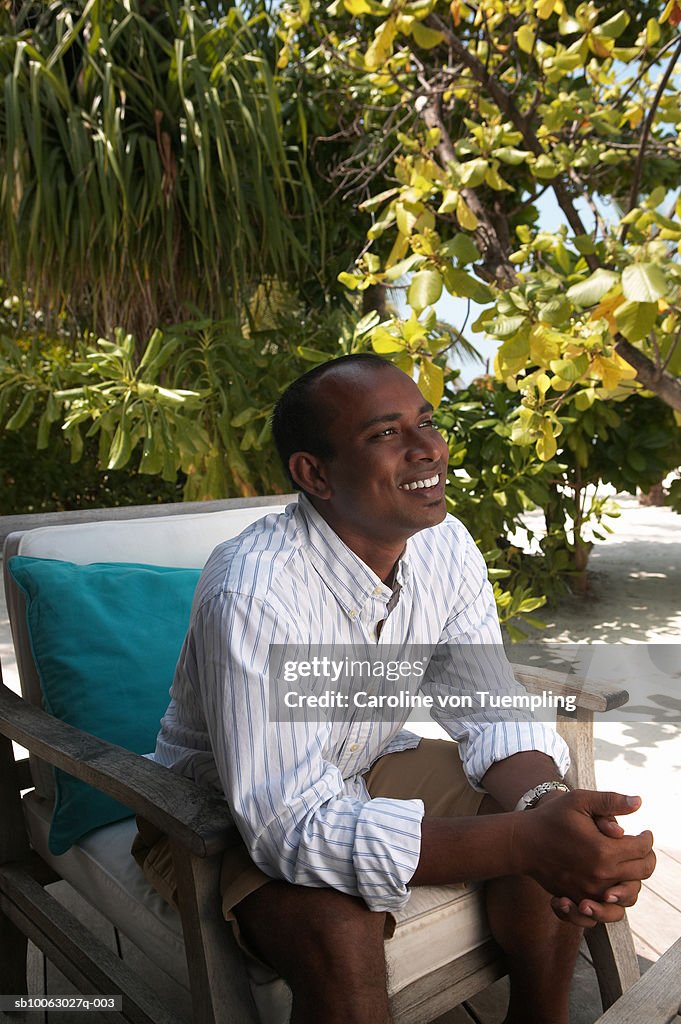 Man sitting on chair, looking away, smiling