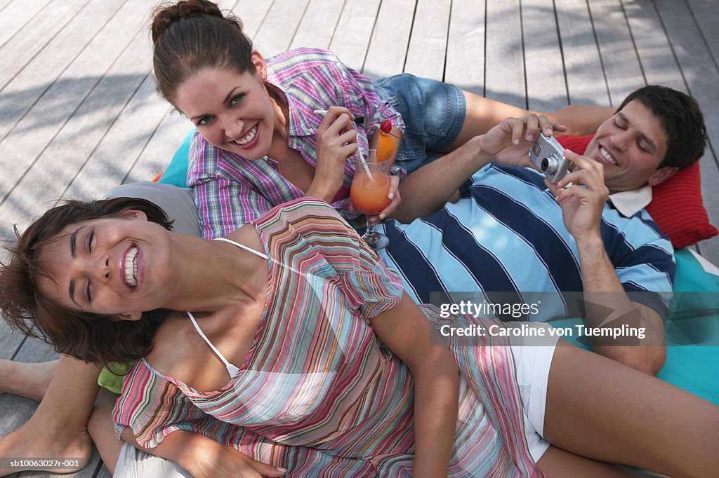 Man lying on pillow with two women, laughing, elevated view