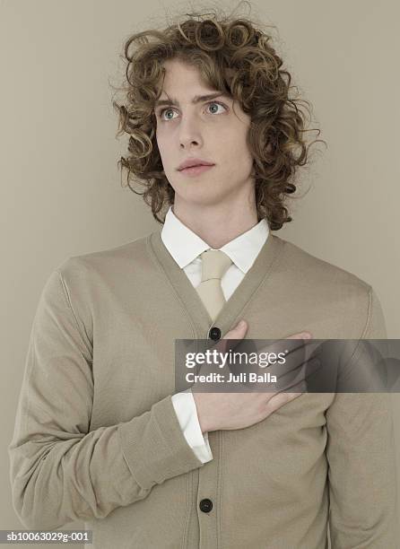 young man hands on chest, looking away, close-up - main sur la poitrine photos et images de collection