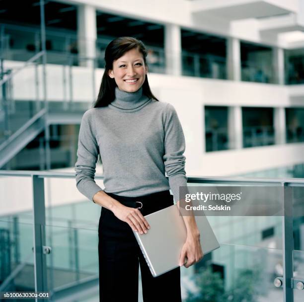 young businesswoman holding laptop, smiling, portrait - standing with laptop imagens e fotografias de stock