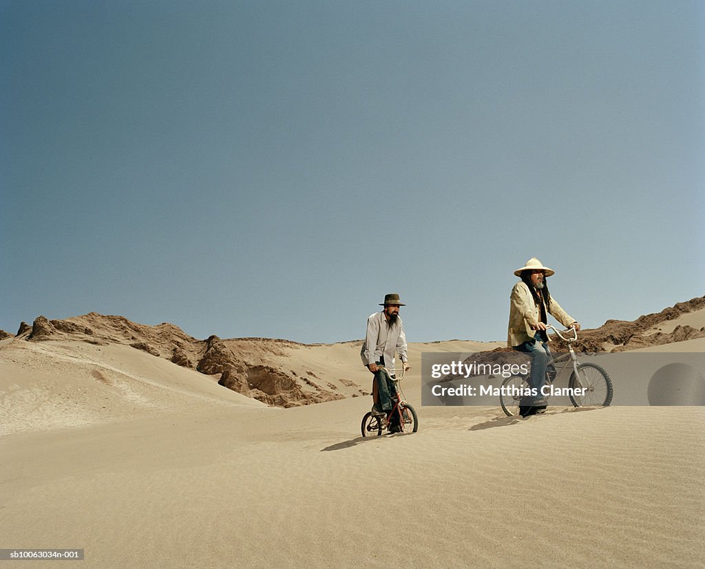 Chile, San Pedro de Atacama, two men riding bicycles in desert