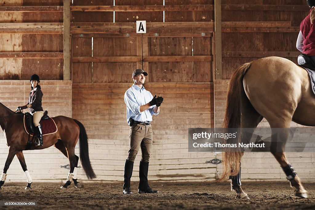 Man Standing Rider Young Man Standing Between To Riders And Their Horses In A Training ...