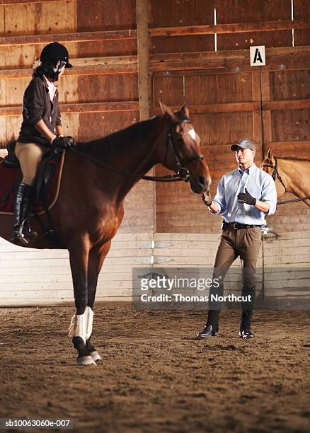 young man standing next to rider and her horse in a training stable - animal trainer stock-fotos und bilder