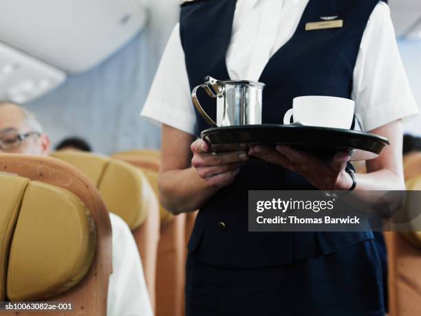 flight attendant holding tray with coffee, mid section - flight attendants stock-fotos und bilder