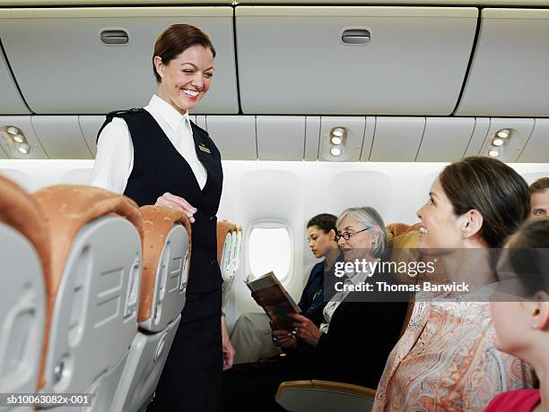 flight attendant talking with passengers including child (10-11) on airplane - tripulación fotografías e imágenes de stock