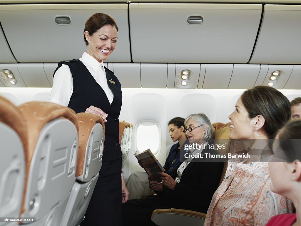 Flight attendant talking with passengers including child (10-11) on airplane