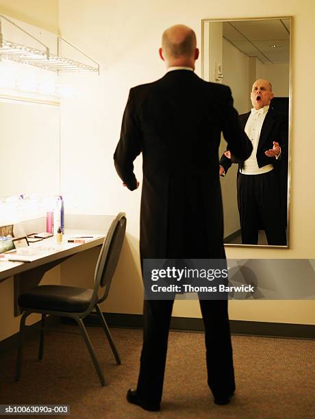 mature male opera singer warming up in dressing room mirror - vestuario entre bastidores fotografías e imágenes de stock