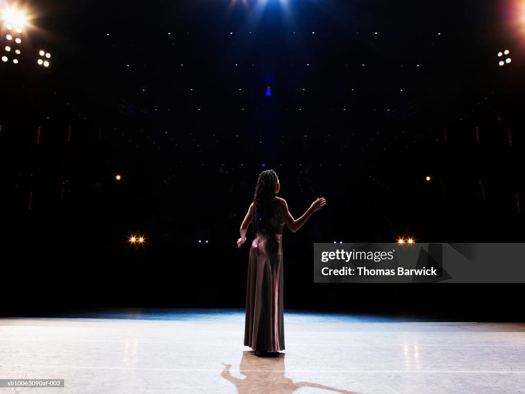 Female opera singer performing solo on stage, rear view